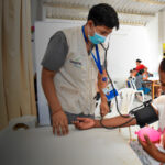 Madre lactante recibiendo control de salud en un centro de atención primaria en Perú, como parte de un programa de bienestar materno-infantil prisma ong peruana